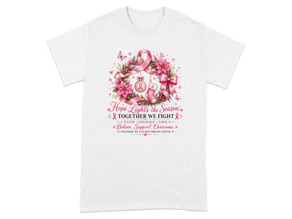 White t-shirt with wreath, pink ribbon, ornament, stocking, and text about fighting breast cancer.