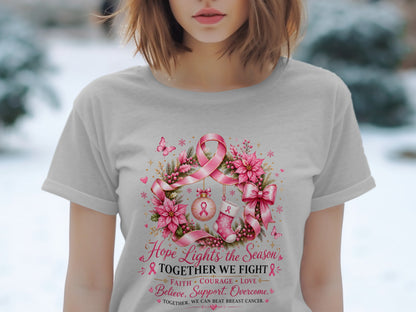 Light pink t-shirt with a floral wreath design featuring a pink ribbon and the text "Hope Lights the Season' Together We Fight".