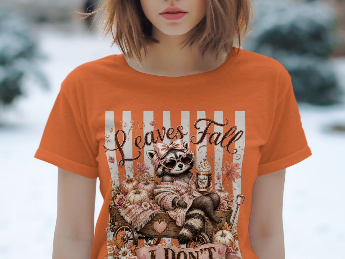 Raccoon in sunglasses with "Leaves Fall" text sits in a wagon of pumpkins.