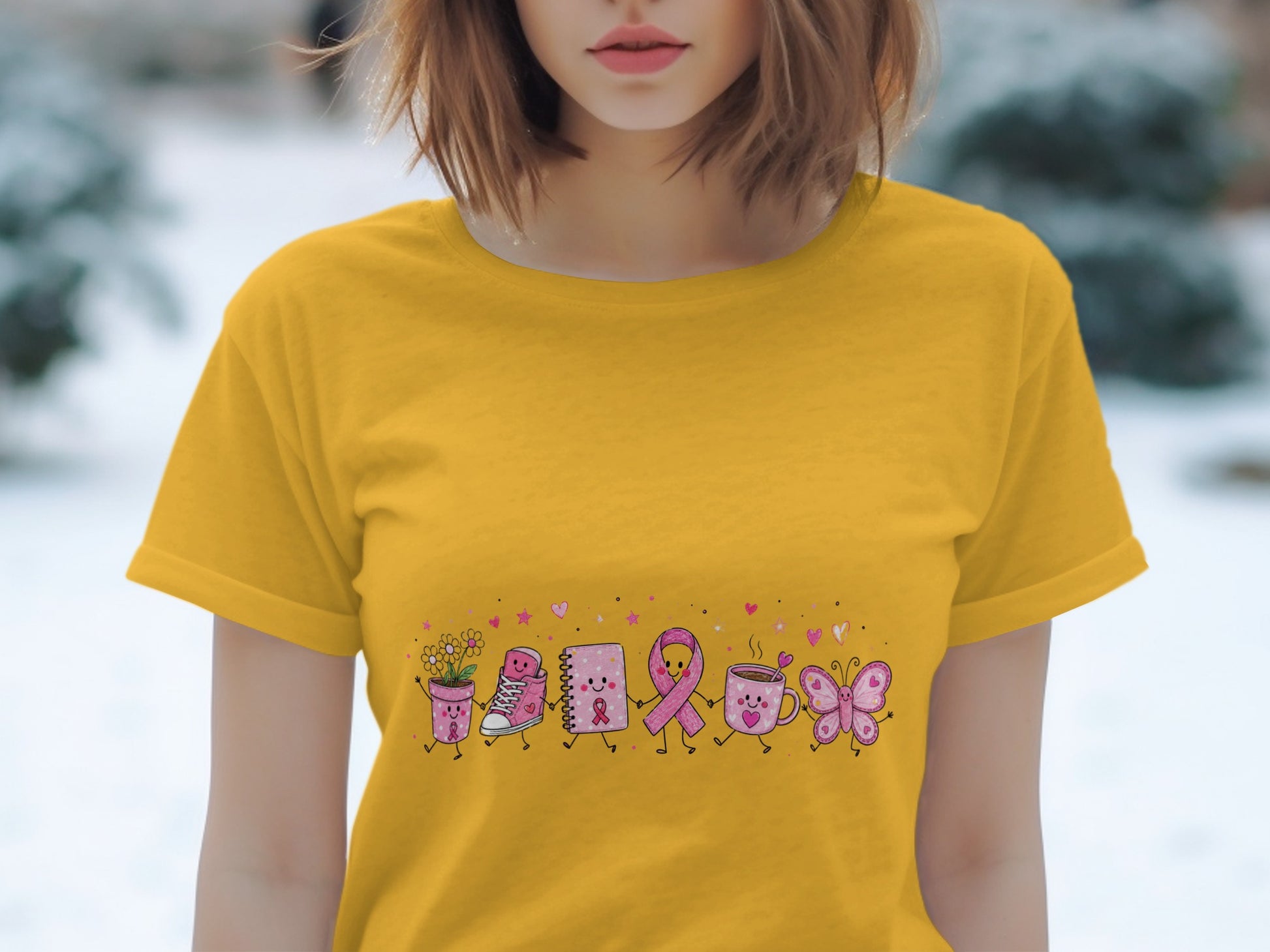 Yellow t-shirt with cartoon pink ribbon, shoe, notebook, cup, and butterfly parade.