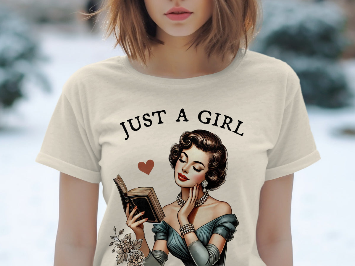 Light beige t-shirt with black text "JUST A GIRL" and vintage woman reading.