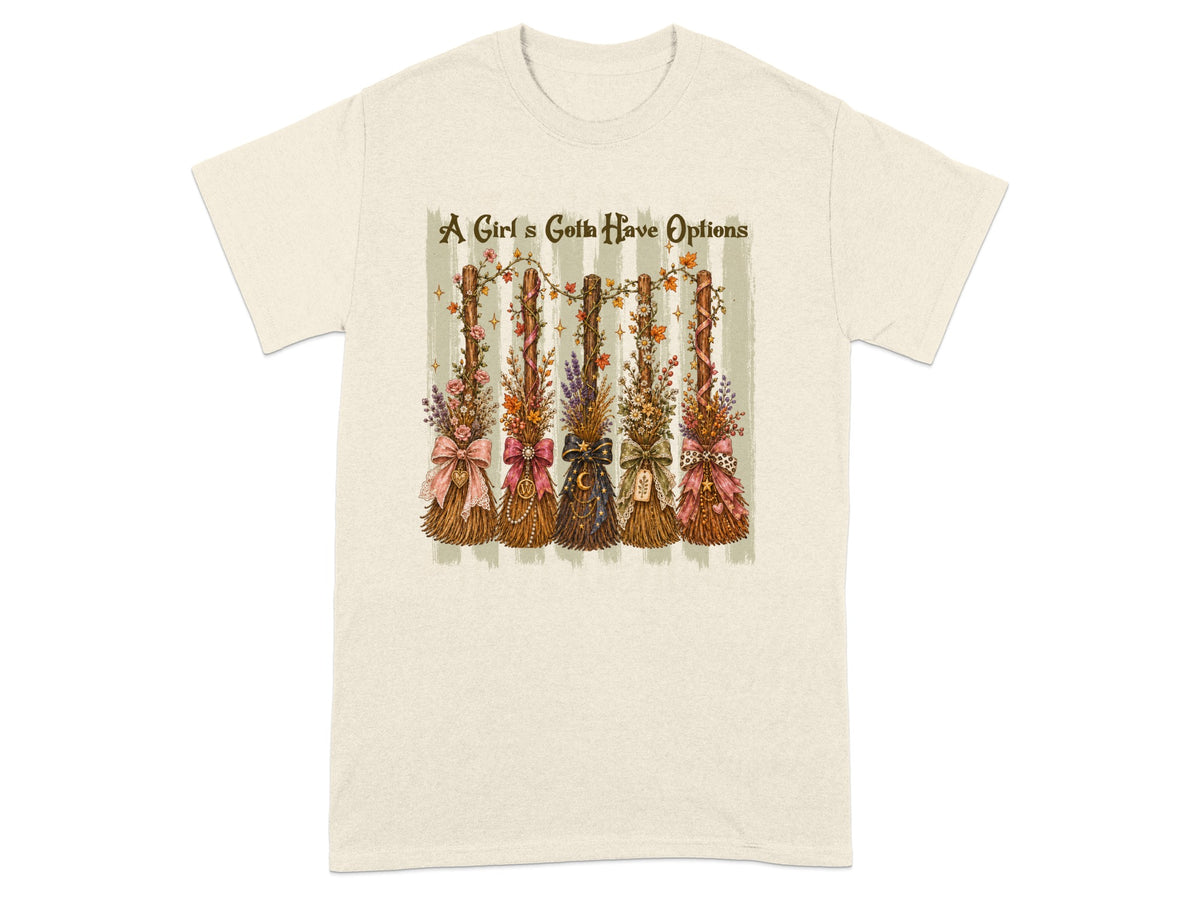 Cream t-shirt with five decorative broomsticks and text "A Girl's Gotta Have Options."