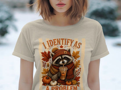 T-shirt graphic of a raccoon in a scarf and hat, drinking from a cup, with text "I IDENTIFY AS A PROBLEM".