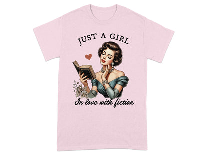 Pink t-shirt with vintage illustration of a woman reading, text "JUST A GIRL In love with fiction".