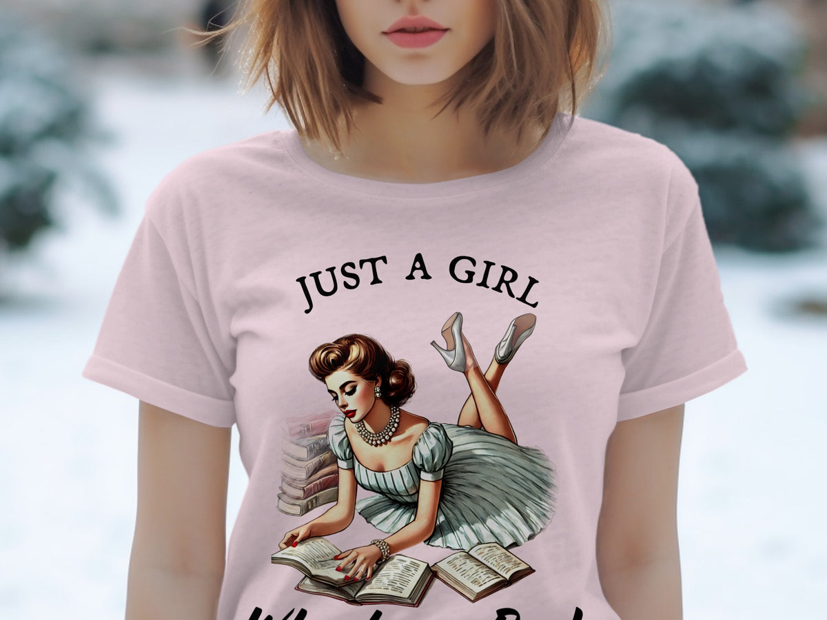 Pink t-shirt with "JUST A GIRL" text and retro illustration of woman reading.