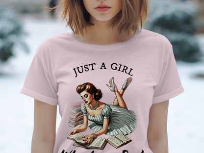 Pink t-shirt with "JUST A GIRL" text and retro illustration of woman reading.