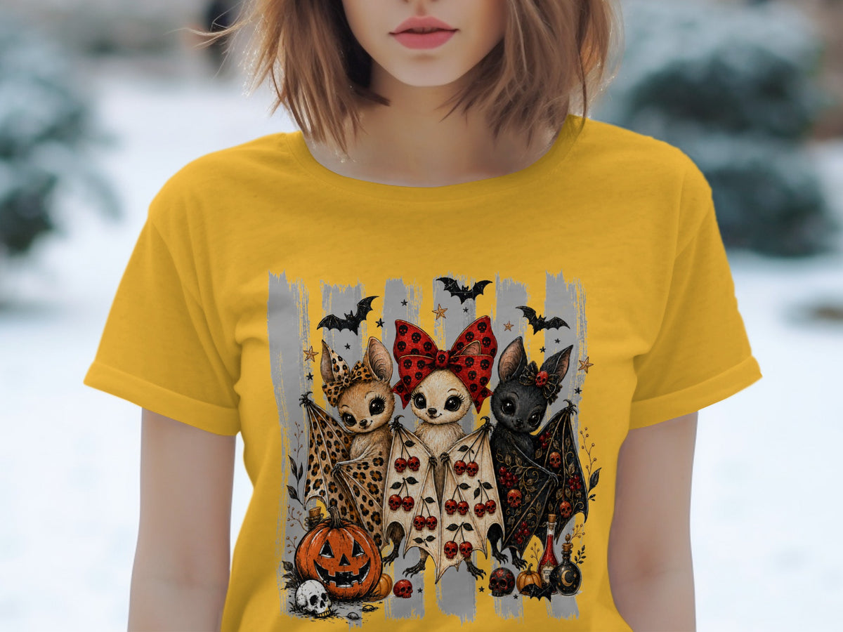 Three cute bats with Halloween decorations on a yellow t-shirt.