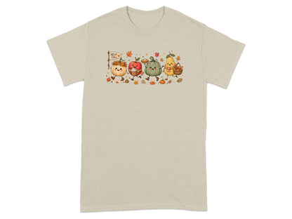 Animated fall characters including pumpkins, apple, and pear on a light tan t-shirt.