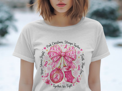 White t-shirt with "Pink Christmas, Stronger Together" graphic featuring pink ribbons, a bow, ornament, and stocking.