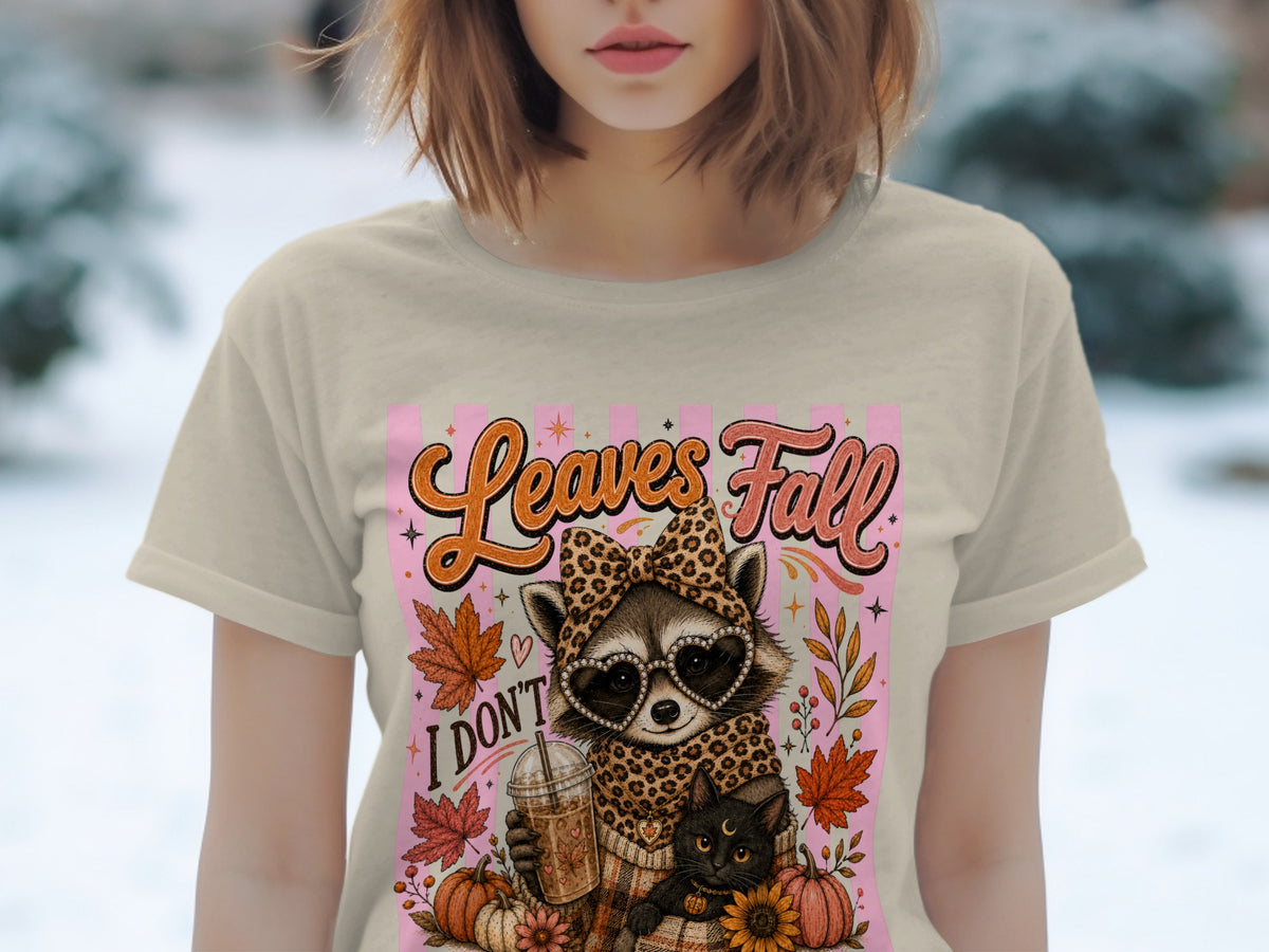 T-shirt graphic with raccoon, cat, coffee, and fall leaves. "Leaves Fall" text.