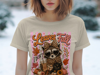 T-shirt graphic with raccoon, cat, coffee, and fall leaves. "Leaves Fall" text.