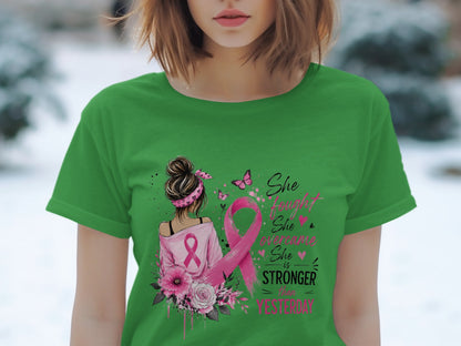 Green t-shirt with breast cancer ribbon, flowers, and "She is stronger than yesterday" text.