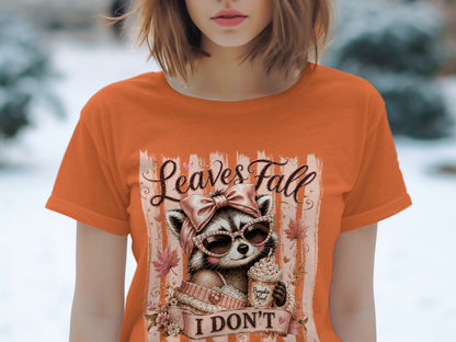 Orange t-shirt with graphic of raccoon in sunglasses, holding a pumpkin spice latte, with text "Leaves Fall I DON'T".