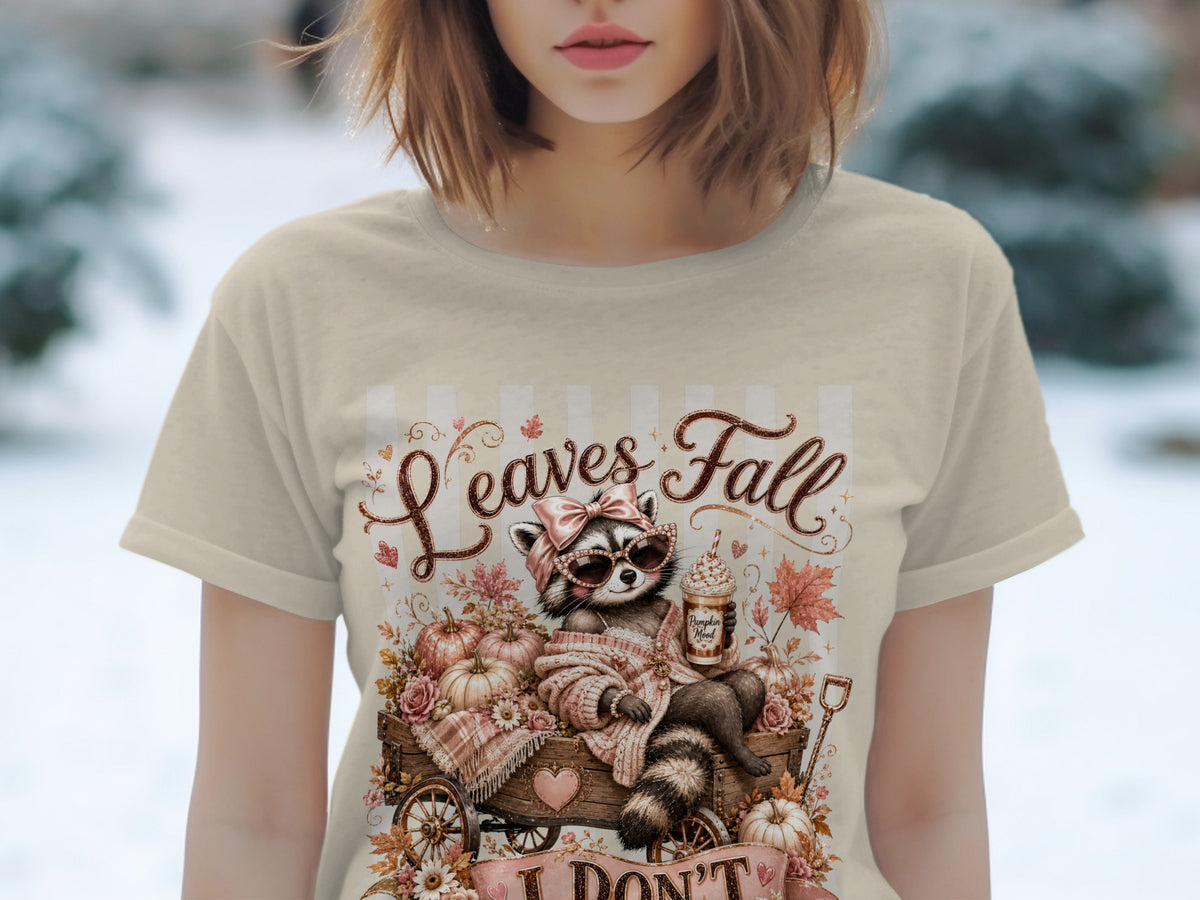 T-shirt graphic with raccoon, pumpkins, and text "Leaves Fall".
