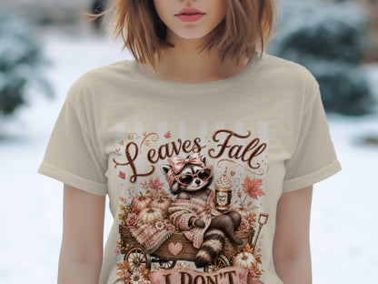 T-shirt graphic with raccoon, pumpkins, and text "Leaves Fall".