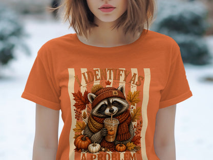 Raccoon with pumpkin spice latte and autumn leaves, text "I IDENTIFY AS A PROBLEM".
