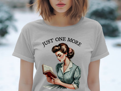 Gray t-shirt with retro illustration of woman reading, "Just One More" text.