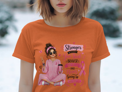 Orange t-shirt with graphic of a woman holding coffee and the words "Stronger Than You Think".