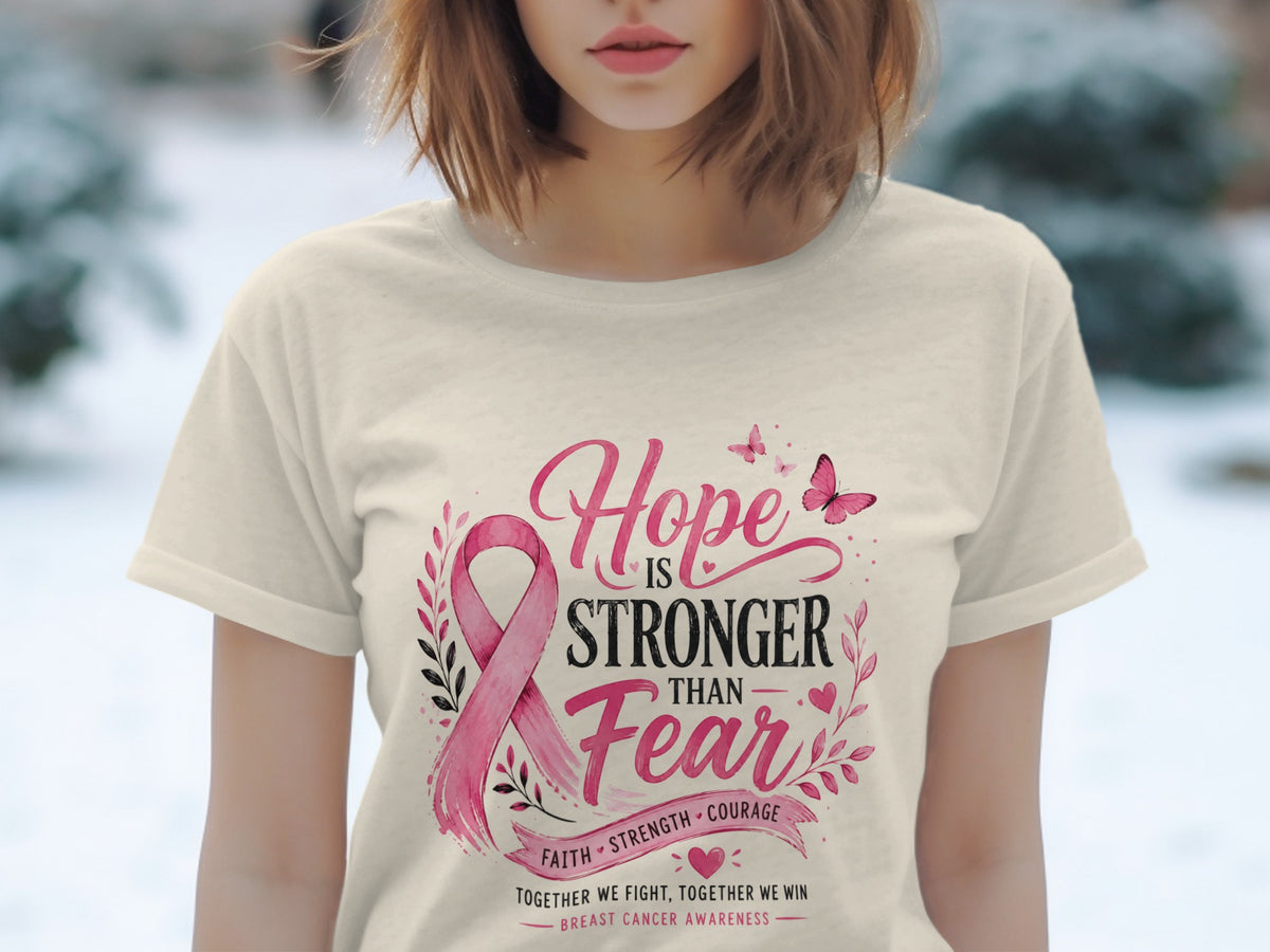 Light cream t-shirt with pink breast cancer ribbon and "Hope is Stronger Than Fear" text.