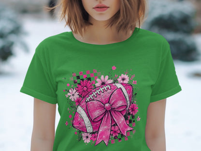 Green t-shirt with a pink football and bow graphic surrounded by flowers and checkered squares.