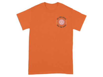 Orange t-shirt with a sun graphic and text "BE THE GOOD SEE THE GOOD".