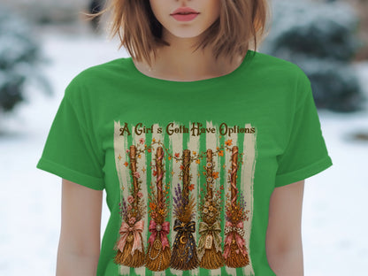 Green t-shirt with "A Girl's Gotta Have Options" and five decorative brooms.
