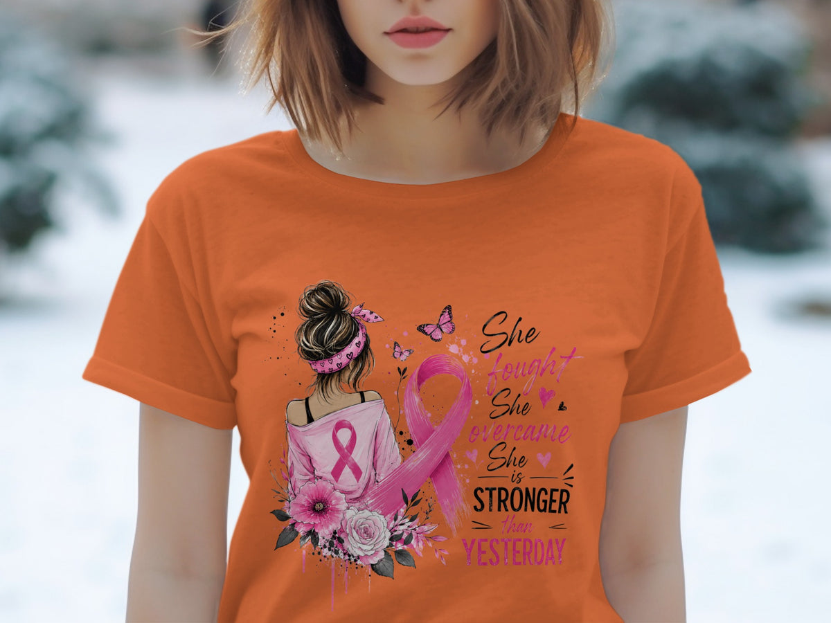 Orange t-shirt with "She fought, she overcame, she is stronger than yesterday" text and pink ribbon.