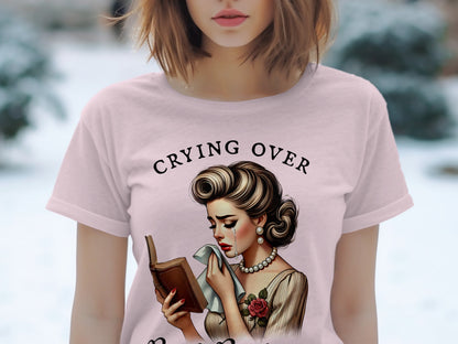 T-shirt graphic: Woman crying over a book, text reads "Crying Over".