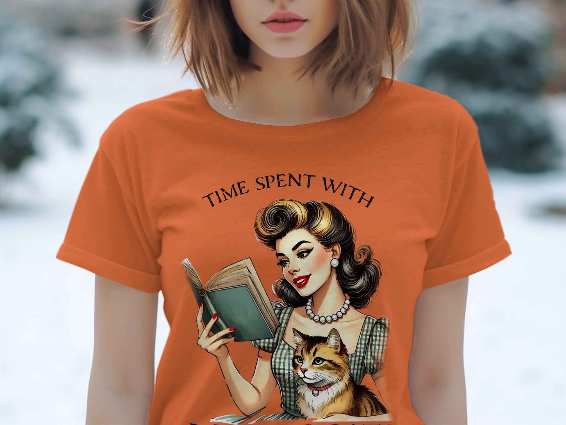 Orange t-shirt with illustration "Time spent with" and a woman reading with a cat.