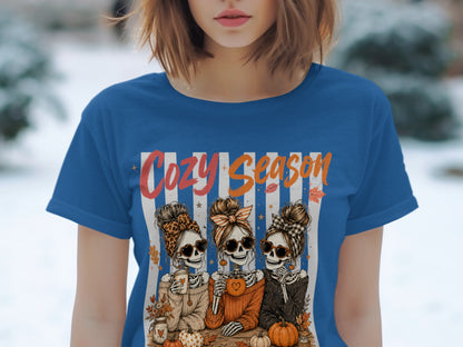 Skeleton friends in sweaters drink from mugs with text "Cozy Season".
