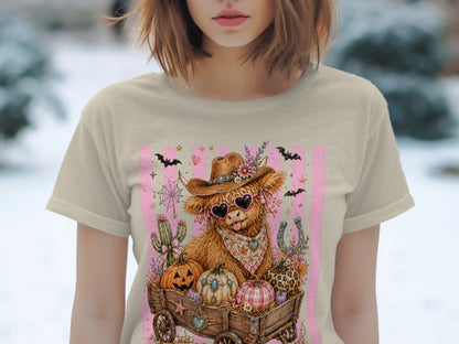 Highland cow wearing cowboy hat and heart sunglasses in a wagon with pumpkins.