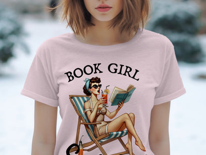 Pink t-shirt with "BOOK GIRL" text and vintage woman reading in lounge chair.