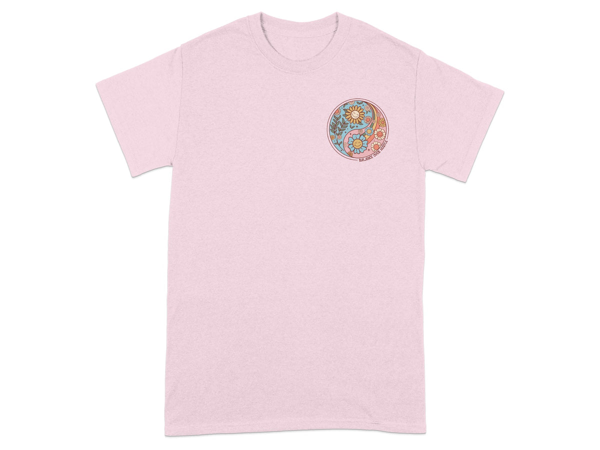 Pink t-shirt with a circular yin yang design featuring flowers and the text "BALANCE OVER HUSTLE".