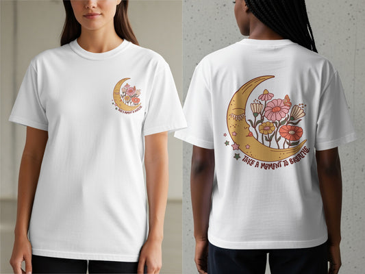 White t-shirt with crescent moon, flowers, and "Take a moment to breathe" text.