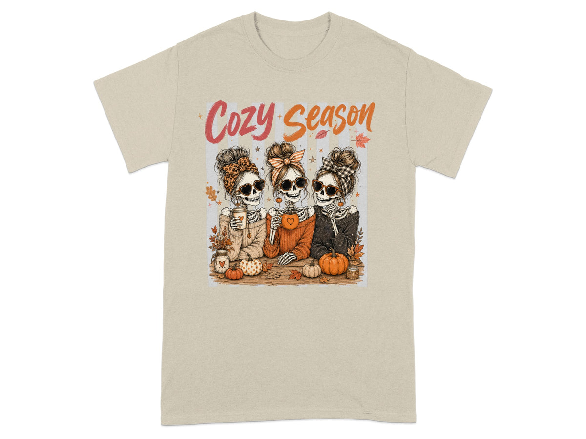 Three skeletons with Halloween accessories, holding drinks, text reads "Cozy Season."