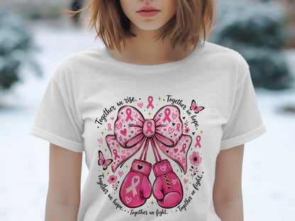 Pink boxing gloves hang from a pink ribbon bow on a white t-shirt.