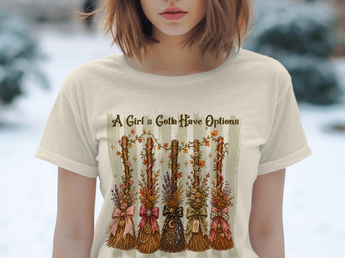 Cream t-shirt with five decorative brooms, text "A Girl's Gotta Have Options".