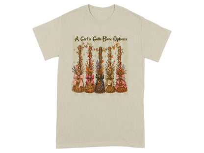 A Girl's Gotta Have Options text above five decorated brooms on a t-shirt.