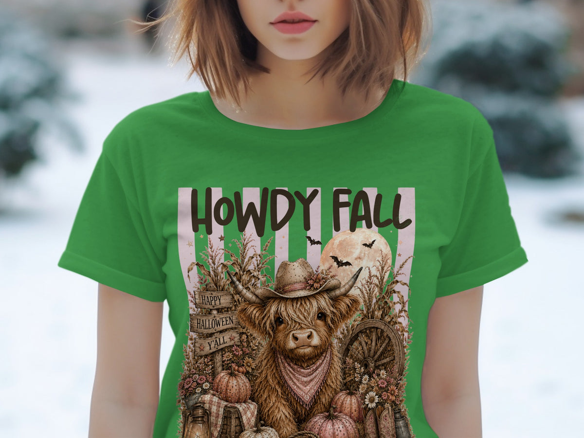 Green t-shirt with Highland cow in cowboy hat, "Howdy Fall" text, pumpkins, and bats.