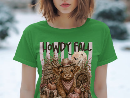 Green t-shirt with Highland cow in cowboy hat, "Howdy Fall" text, pumpkins, and bats.
