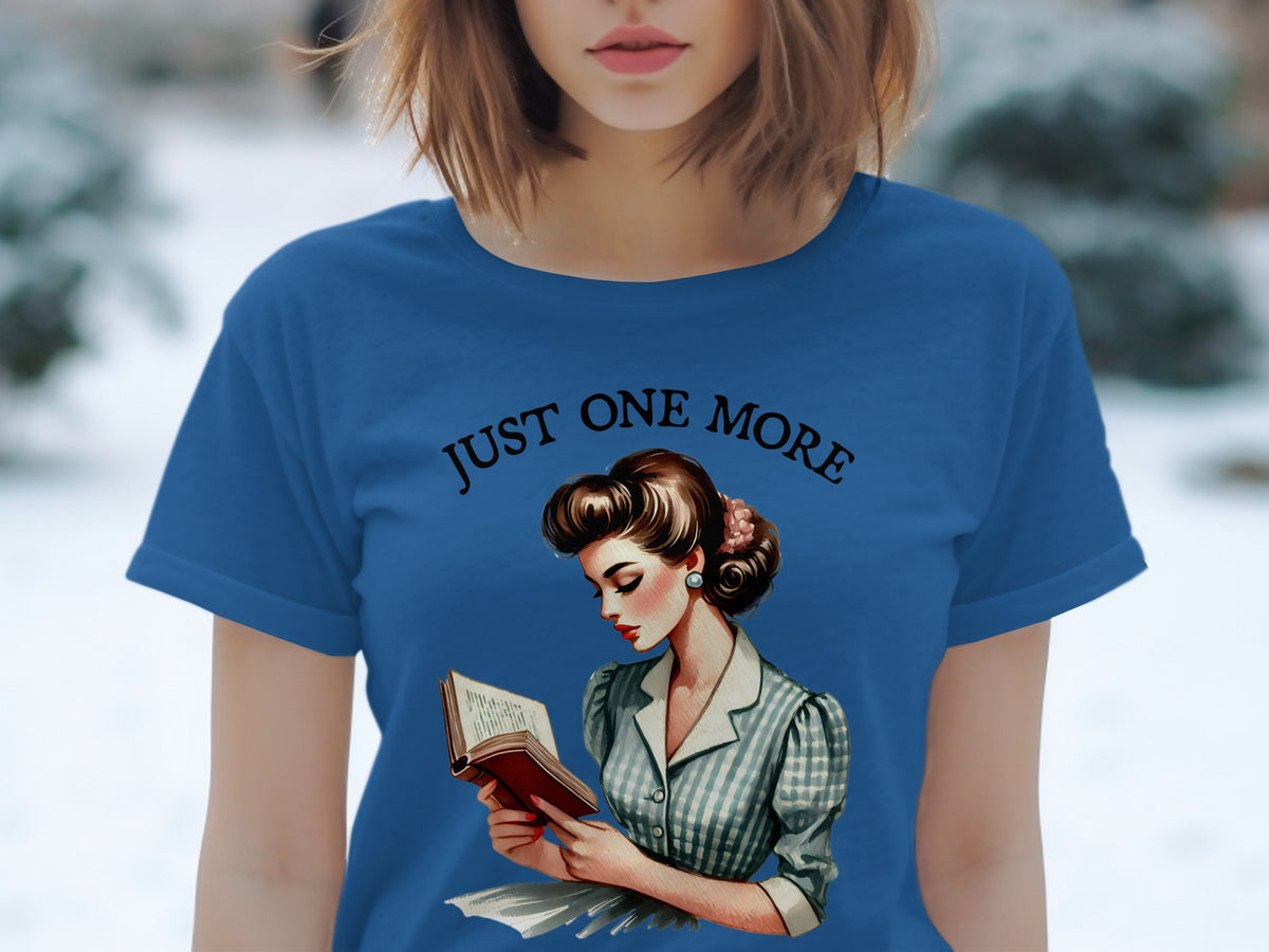 Blue t-shirt with "JUST ONE MORE" and a retro illustration of a woman reading.