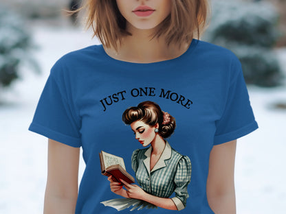 Blue t-shirt with "JUST ONE MORE" and a retro illustration of a woman reading.
