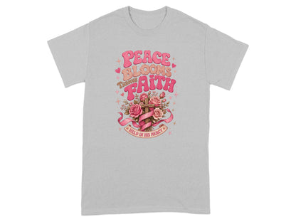 Graphic t-shirt with text "Peace Blooms Through Faith Held in His Mercy" and floral cross.