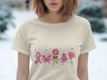 Cream t-shirt with cartoon breast cancer ribbon, butterfly, flower, shoe, and balloon characters.