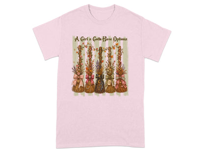Pink t-shirt with five decorative brooms and the text "A Girl's Gotta Have Options".