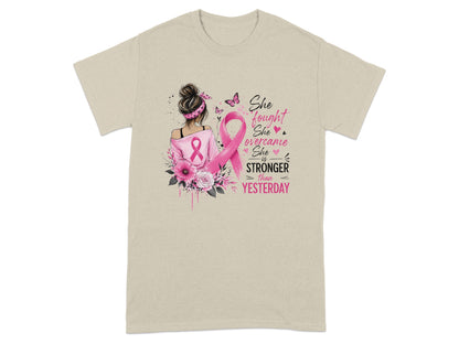 T-shirt with illustration of woman, pink ribbon, flowers, and text "She fought, She overcame, She is STRONGER than YESTERDAY."