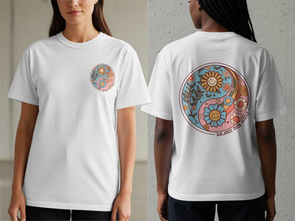 White t-shirt with a yin-yang design featuring smiling flowers and the text "BALANCE OVER HUSTLE."