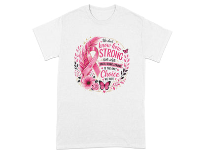 White t-shirt with breast cancer ribbon and "We don't know how strong we are until being strong is the only choice we have" text.