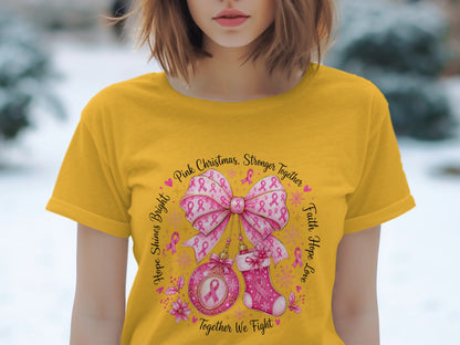 Yellow t-shirt with a circular design featuring pink ribbons, a bow, ornament, stocking, and text.