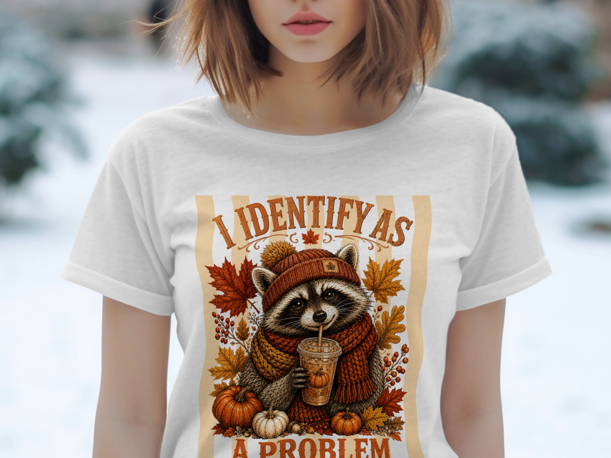 White t-shirt featuring a raccoon in a hat and scarf drinking from a cup with "I identify as a problem" text.